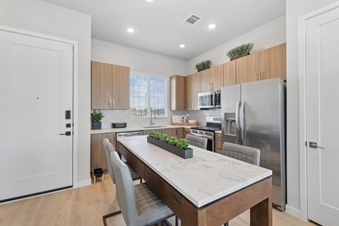 A modern kitchen with a wooden table and grey chairs.