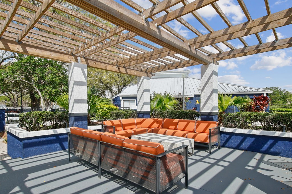 a covered patio with orange couches and a pool