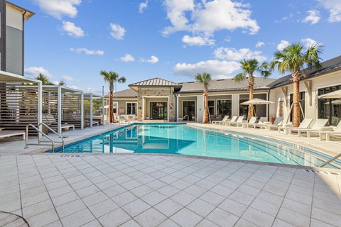 a swimming pool with chairs and palm trees in front of a house