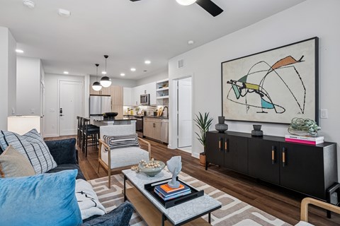 A living room with a large painting on the wall and a coffee table in the center.