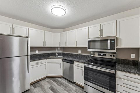 A kitchen with white cabinets and a stainless steel refrigerator.