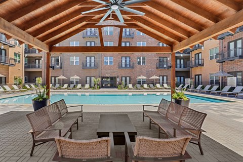 A patio with a table and chairs overlooking a pool.