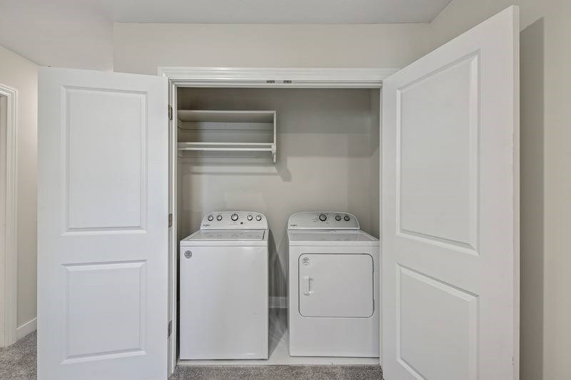 Two white front load washing machines in a laundry room.