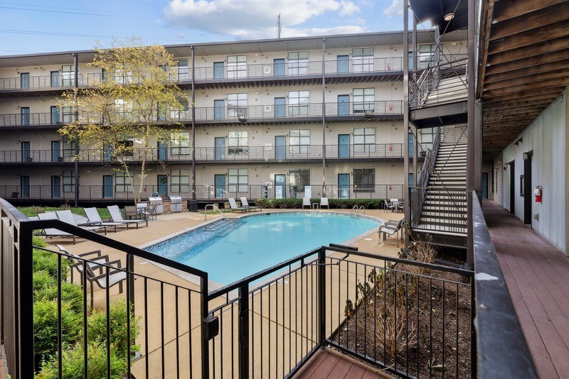 a swimming pool is in the middle of a building with a staircase and a balcony