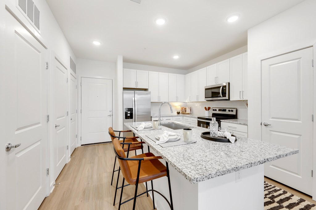 a large kitchen with white cabinets and a marble counter top