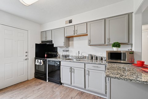 A kitchen with a black oven and white cabinets.