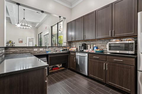 A kitchen with dark wood cabinets and a black counter top.