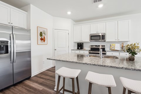 A kitchen with white cabinets and a granite countertop.
