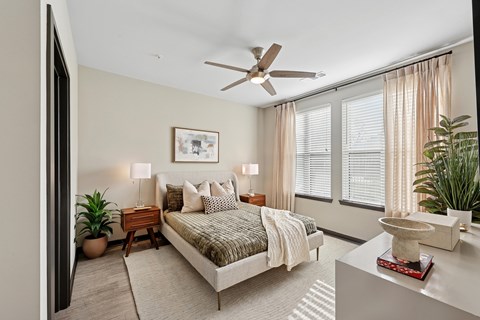 A bedroom with a bed, nightstand, and a ceiling fan.