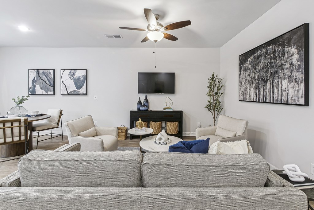 a living room with a couch and chairs and a ceiling fan