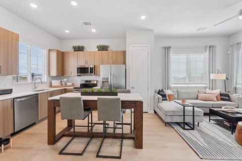 A modern kitchen with a dining table and a living room area.
