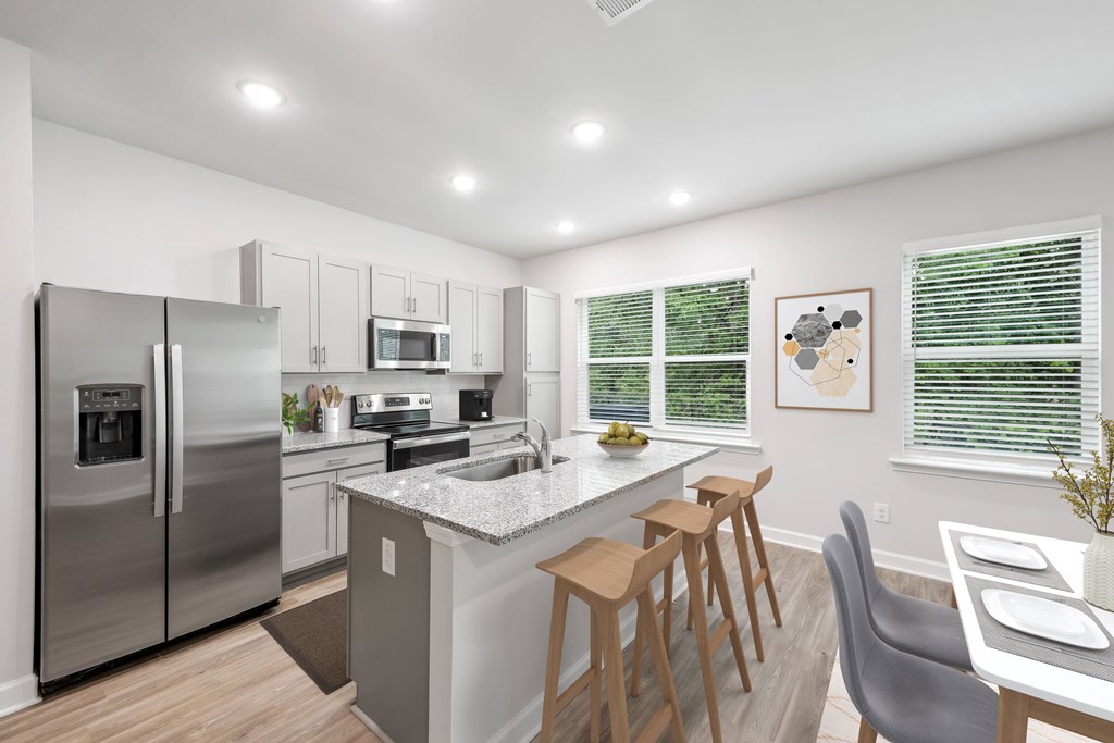 an open kitchen and dining area with stainless steel appliances and a marble counter top