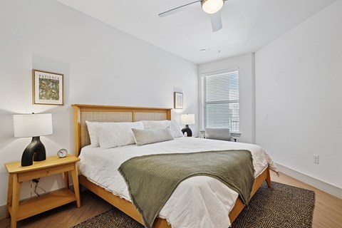 A bedroom with a bed, nightstand, and window.