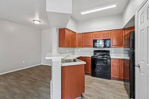 A kitchen with brown cabinets and black appliances.