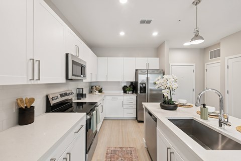 A modern kitchen with white cabinets and stainless steel appliances.