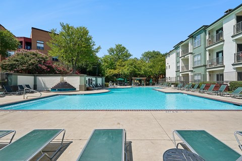 A large swimming pool surrounded by lounge chairs and trees.