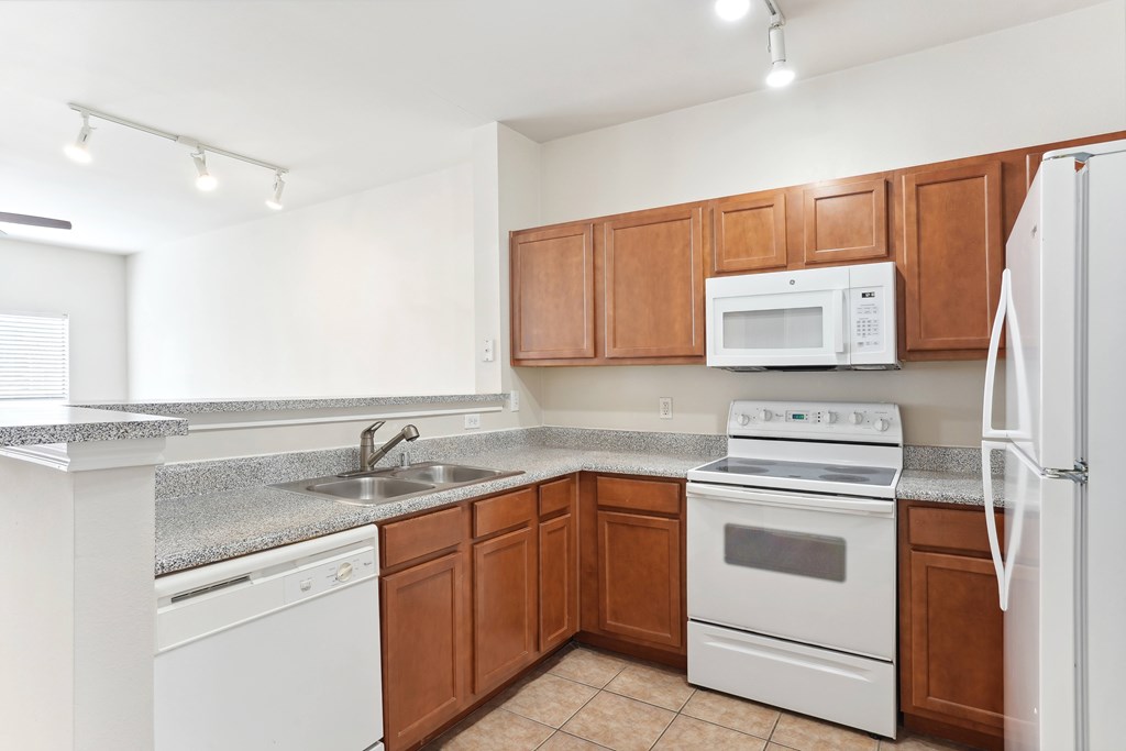 Traditional style kitchen with white appliances and wooden cabinets and granite counter tops