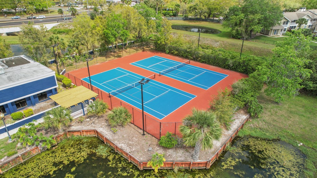 an aerial view of a tennis court with trees and a house on the side