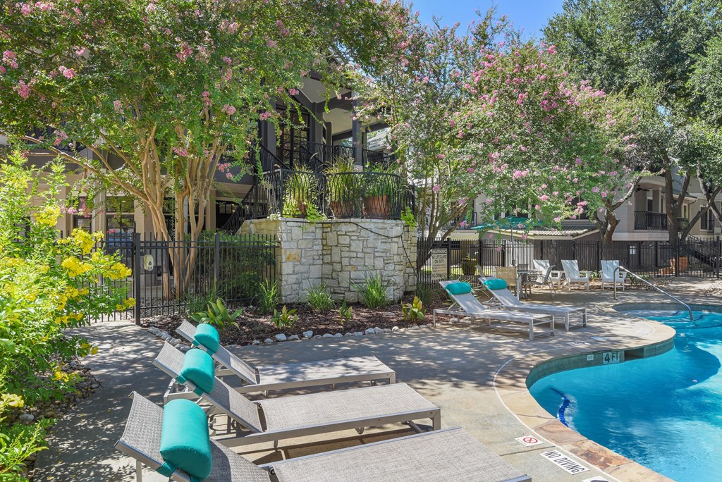 a pool with lounge chairs and trees in the background