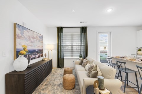A living room with a large painting on the wall and a couch with a yellow throw pillow.