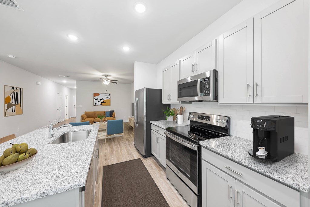 a kitchen with white cabinets and black appliances and counter tops