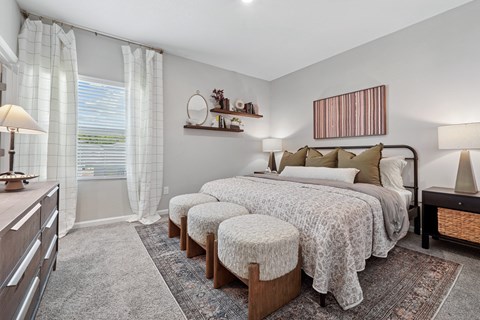 A bedroom with a large bed, a window with curtains, and a wooden dresser.