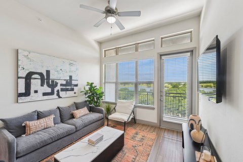 A living room with a grey couch and a painting on the wall.