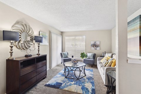 A living room with a white couch, a coffee table, and a large mirror on the wall.