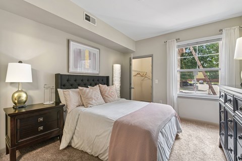 A bedroom with a large bed and a nightstand with a lamp.