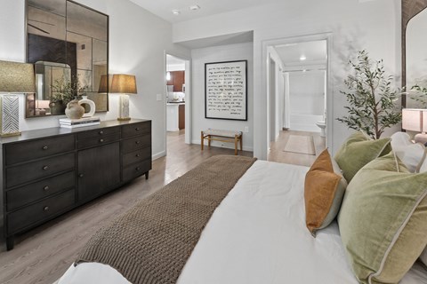 A bedroom with a large bed and a dresser with a mirror above it.