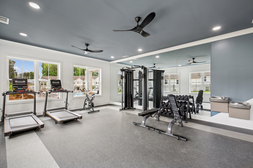 a gym with weights and cardio equipment and windows