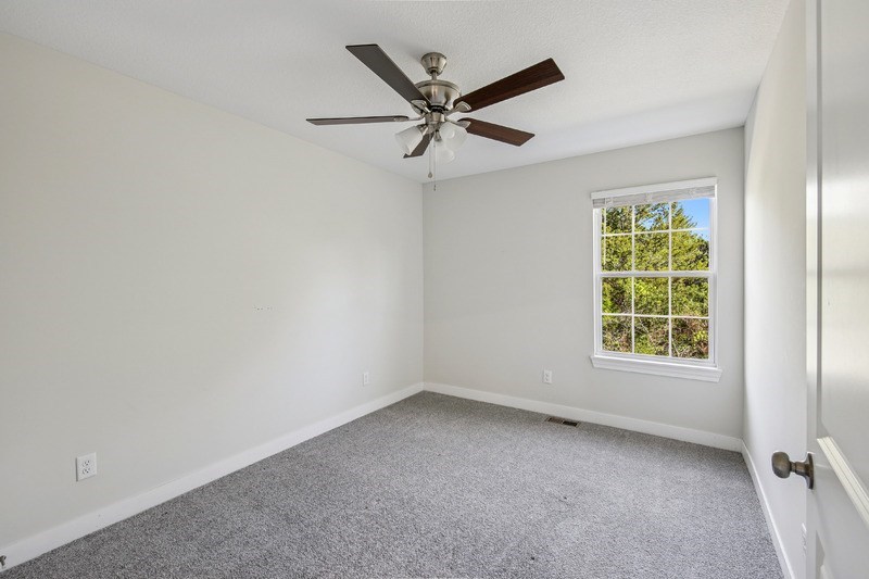 A room with a ceiling fan and a window.