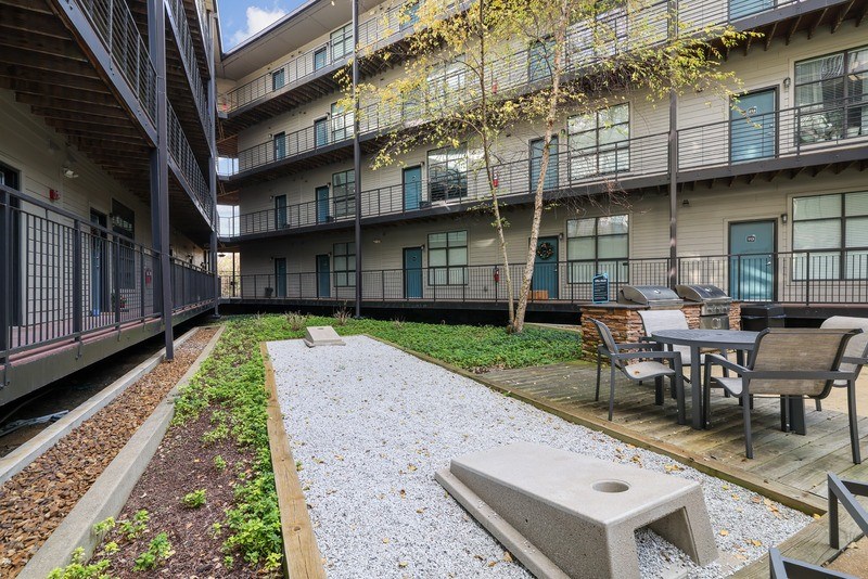 a courtyard with tables and chairs outside of an apartment building