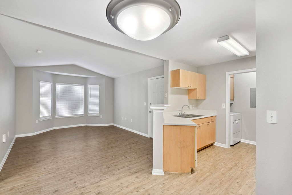living area with wood style cabinets in kitchen and vaulted ceiling