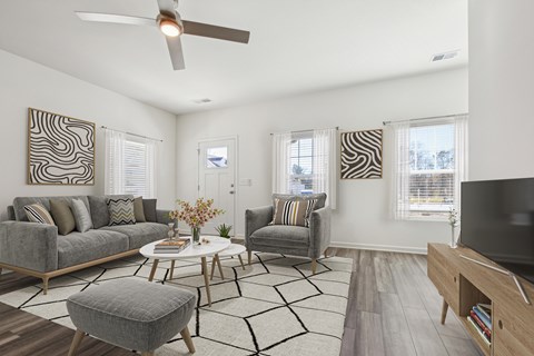 A living room with a grey couch, a white coffee table, and a television on a wooden stand.