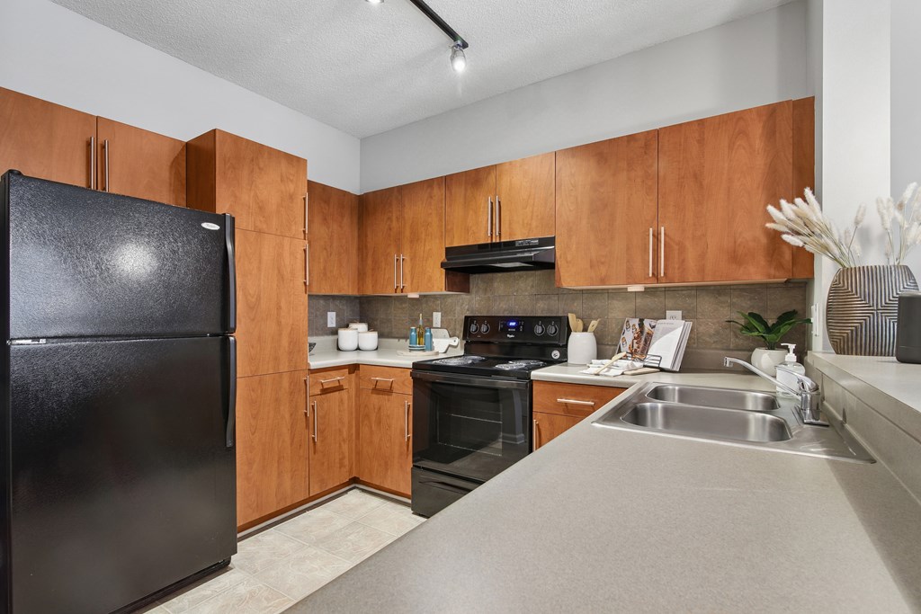 A kitchen with wooden cabinets and a black refrigerator.