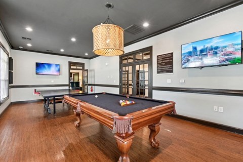 A room with a pool table and a television mounted on the wall.