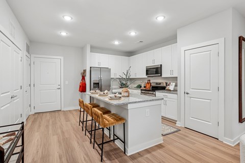A kitchen with white cabinets and a wooden floor.