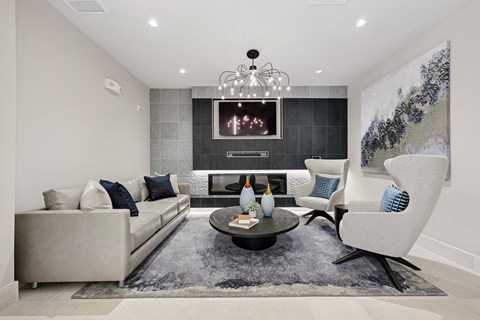 A modern living room with a grey sofa, a black coffee table, and a large painting on the wall.