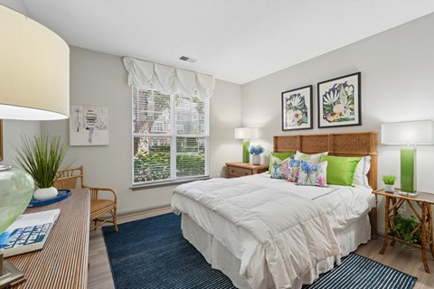 A bedroom with a large bed and a window with blinds.