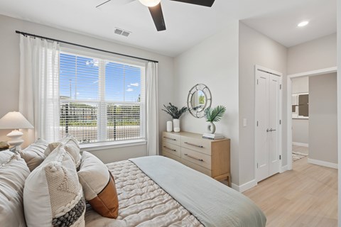 A bedroom with a large bed and a window with blinds.