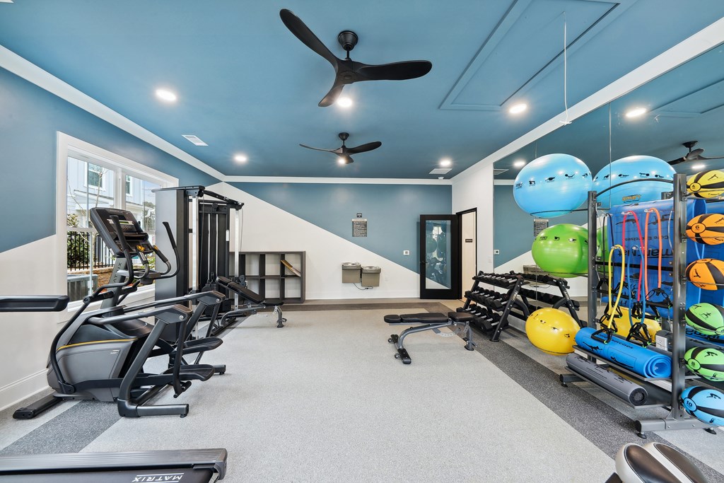 a home gym with exercise equipment and a ceiling fan