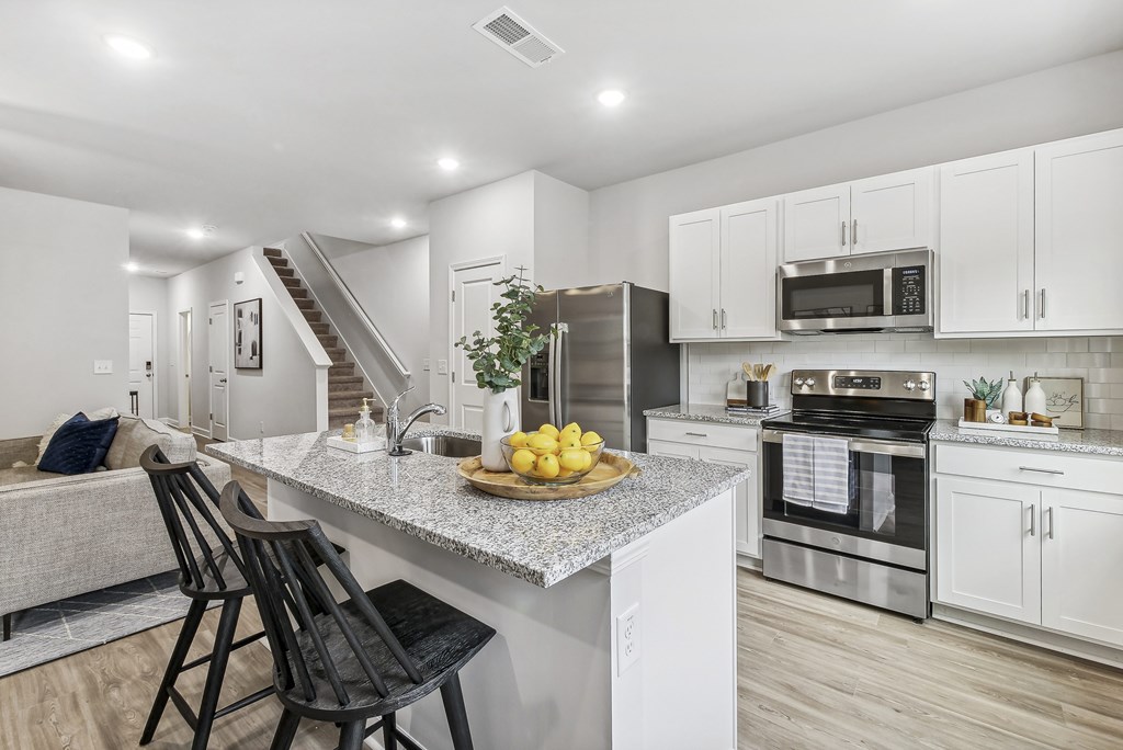 an open kitchen and living room with a marble counter top
