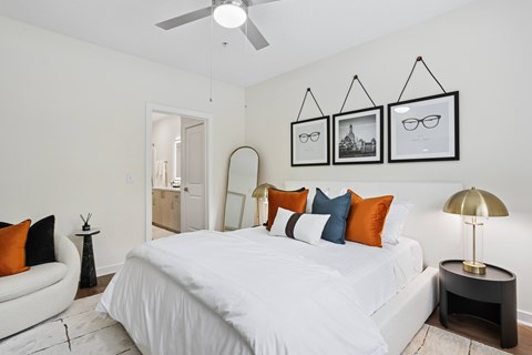 A bedroom with a white bed and a white ceiling fan.