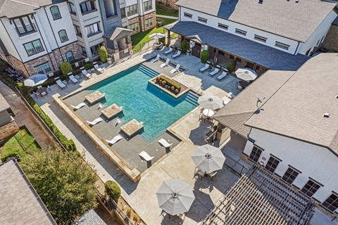 an aerial view of an outdoor pool with chairs and umbrellas and a house