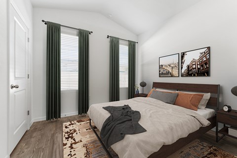 A bedroom with a bed, two pictures on the wall, and a rug on the floor.