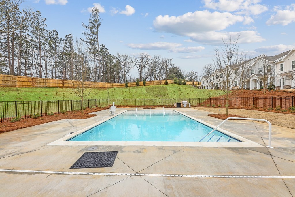 a swimming pool with a fence and a house in the background