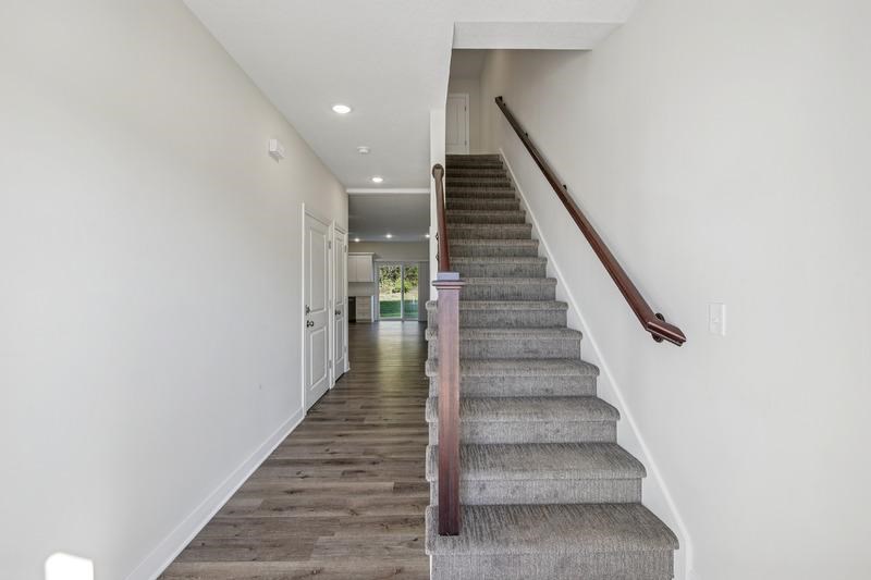 A staircase with a wooden handrail and carpeted steps leads to a doorway.