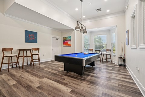 A pool table is in the middle of a room with wood flooring.