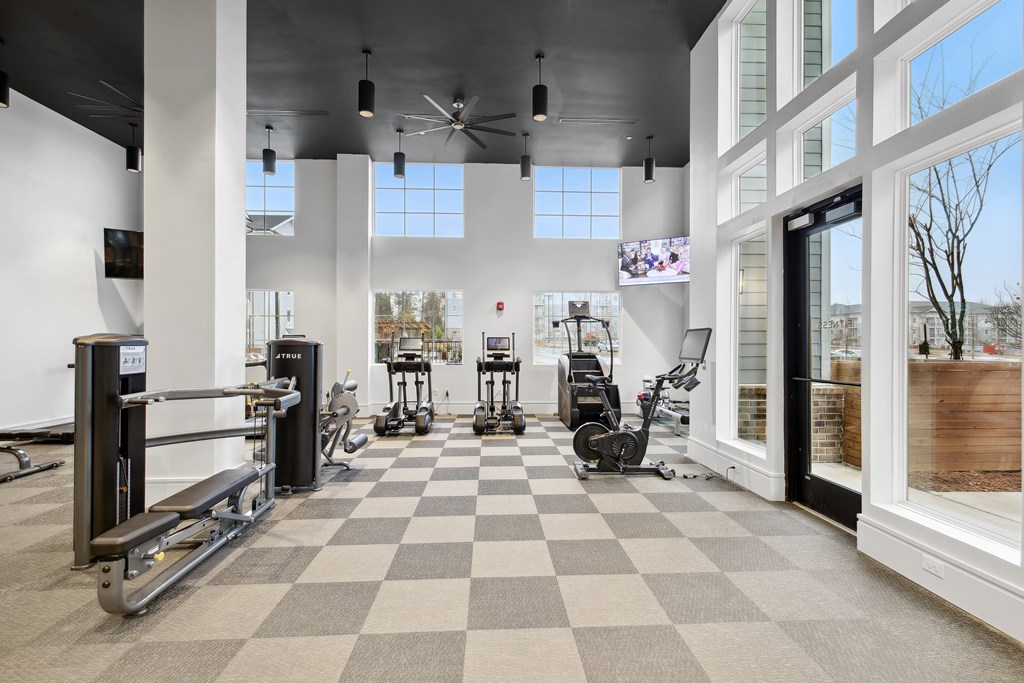 a gym with weights and cardio equipment in a building with large windows